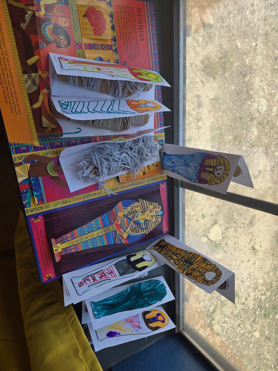 Children's illustrated sarcophagus drawings displayed on a windowsill