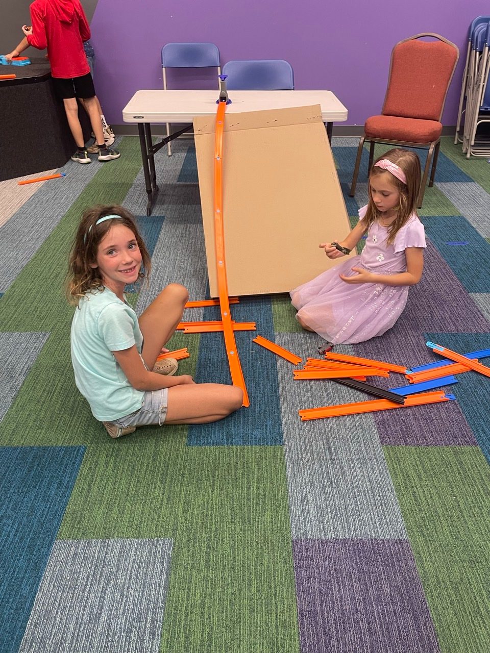 Two children building and testing a ramp on the floor